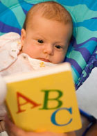 a young baby looking at an ABC book